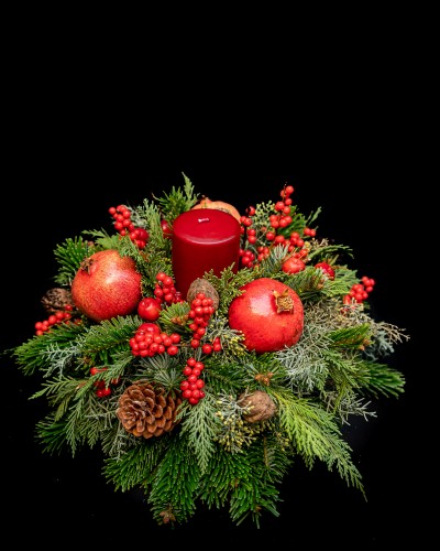 Arrangement of pomegranates, cinnamons, ilex, conifer cones, fir and. red candle.