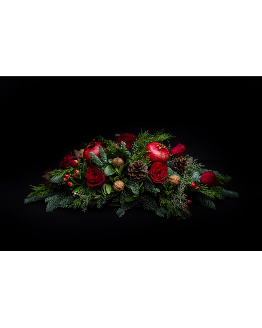 Arrangement of pomegranates, conifer cones, fir, walnuts and red roses.